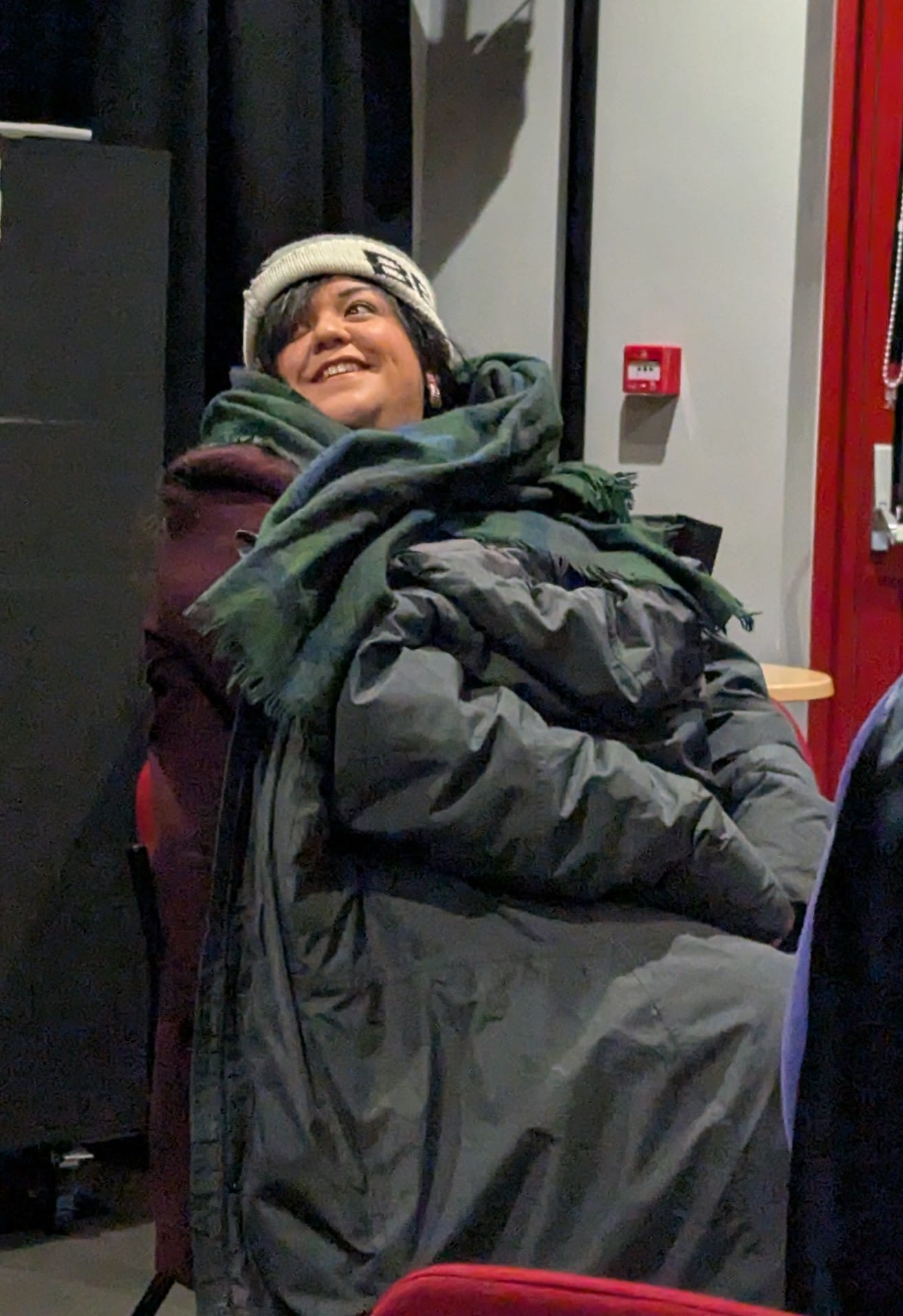 A member of the KTB Music Theatre Chorus keeping warm in a big coat, scarf and woolly hat